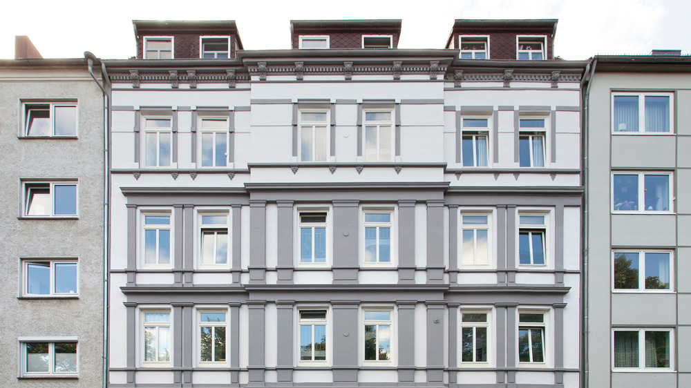 Mehrstöckiger Altbau mit grau und weiß gestrichener Fassade