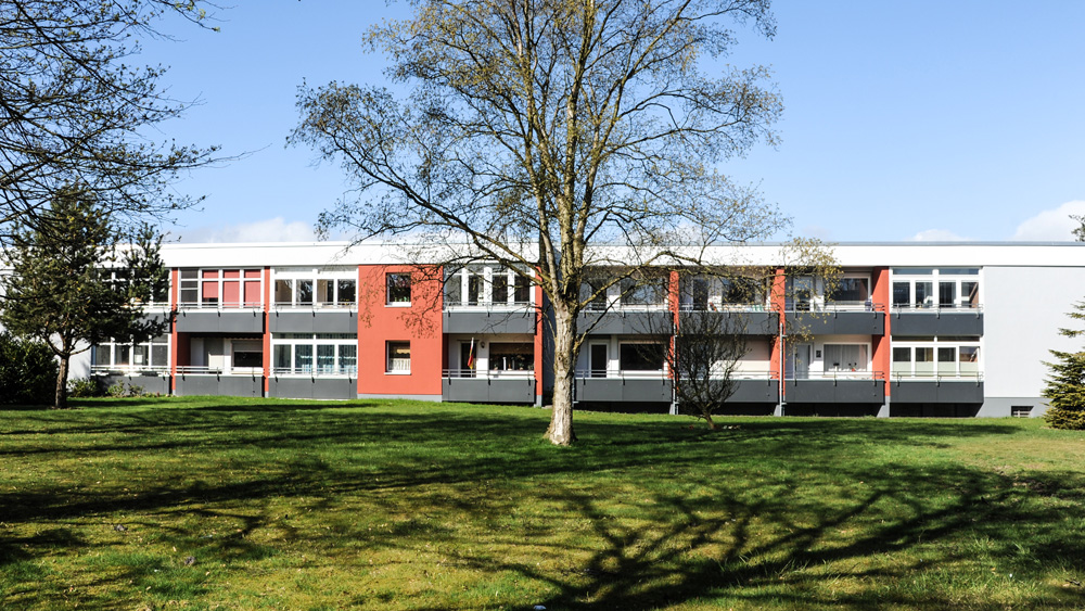 Langgezogenes, einstöckiges Gebäude mit rot-grau-weiß gestrichener Fassade